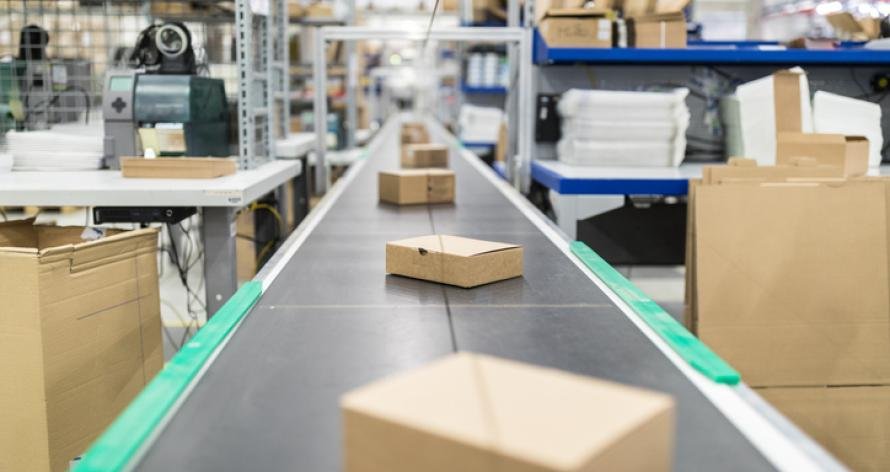 Cardboard boxes on moving belt conveyor at distribution warehouse. Modern warehouse with automatic moving conveyor machine.